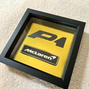 McLaren P1 enamel badge framed and mounted on 18ct gold heat reflecting material